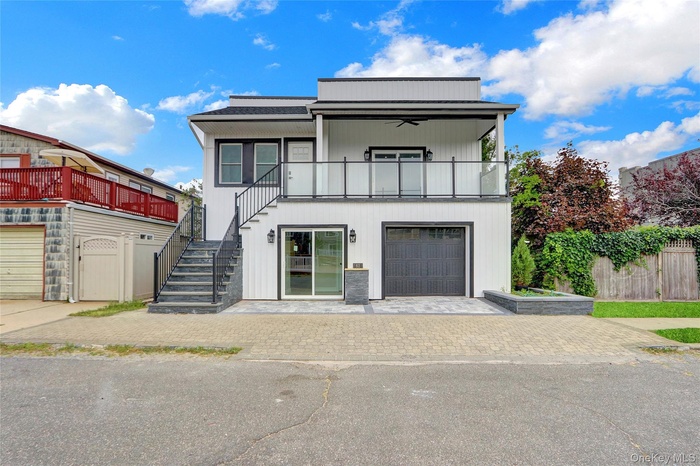 View of front of house featuring stairs, a ceiling fan, decorative driveway, and a garage