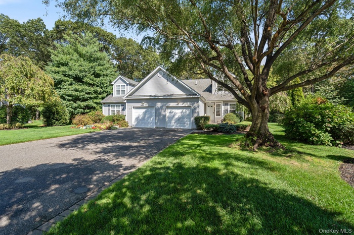 View of front of property with asphalt driveway, a front yard, and a garage