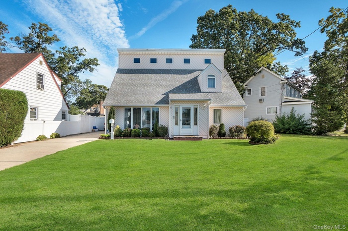 Rear view of property featuring a shingled roof and concrete driveway
