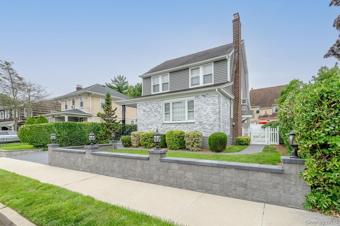 View of front facade featuring stone siding and a chimney