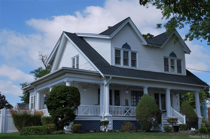 View of front of house with roof with shingles, a porch, and a front yard