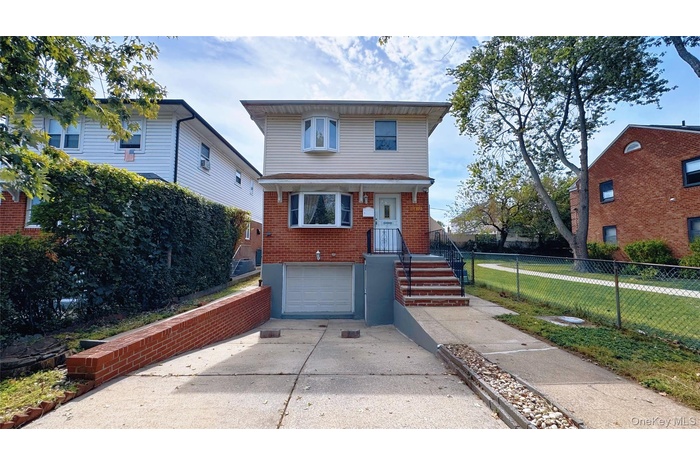 American foursquare style home with driveway, brick siding, and a garage