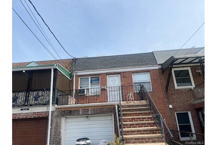 View of front of property featuring a balcony, brick siding, a shingled roof, stairs, and an attached garage