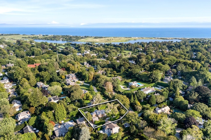 Aerial view of residential area with property boundaries highlighted and a nearby body of water