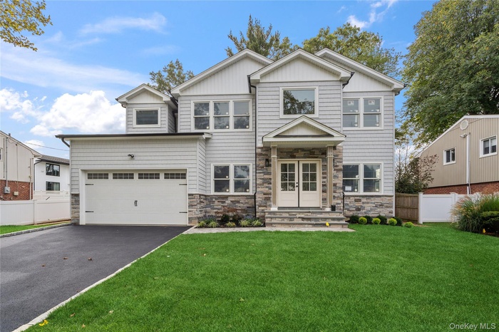 View of front facade with driveway, stone siding, a garage, and board and batten siding
