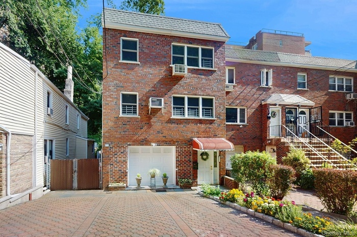 Traditional-style house with brick siding, decorative driveway, a garage, and a gate