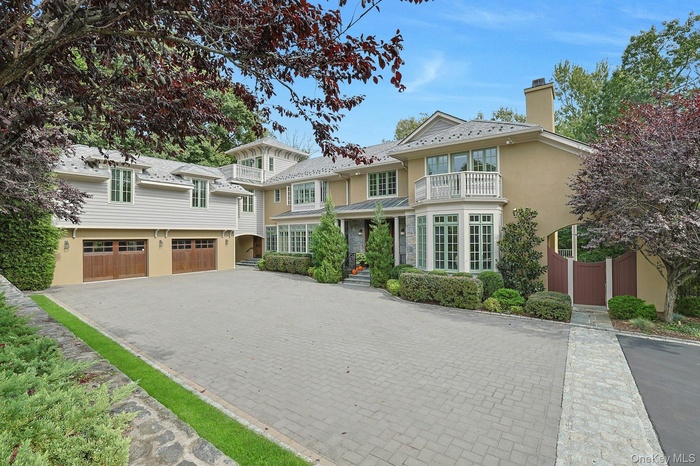 View of front of house with a chimney, decorative driveway, a balcony, a garage, and stucco siding