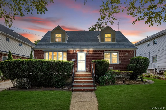 Cape cod-style house with a lawn and brick siding
