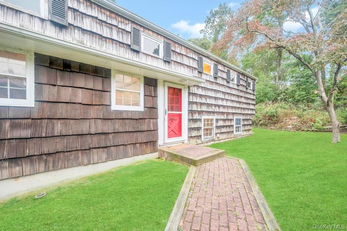 Doorway to property featuring a lawn