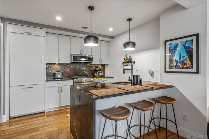 Kitchen featuring dark countertops, a breakfast bar, visible vents, and appliances with stainless steel finishes