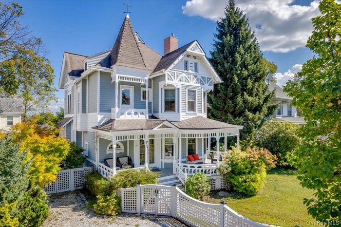 front view of property featuring a porch, a chimney, and a shingled roof