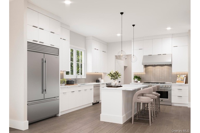 Kitchen with modern cabinets, white cabinetry, a breakfast bar area, high end appliances, and recessed lighting