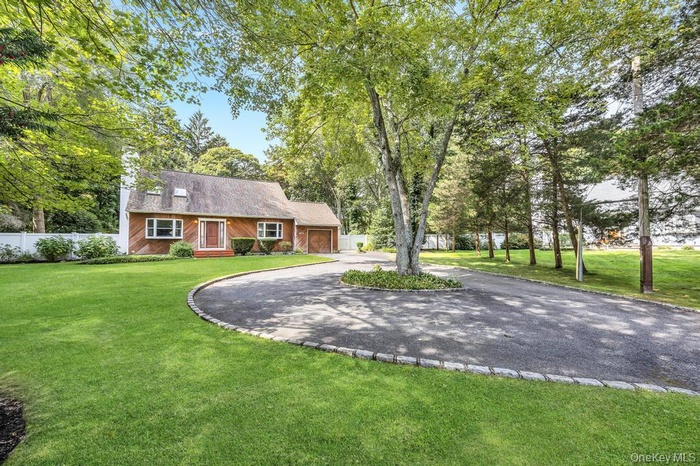 View of front of house with curved driveway and view of wooded area