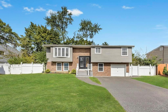 High Ranch featuring Vinyl siding, driveway, and a garage