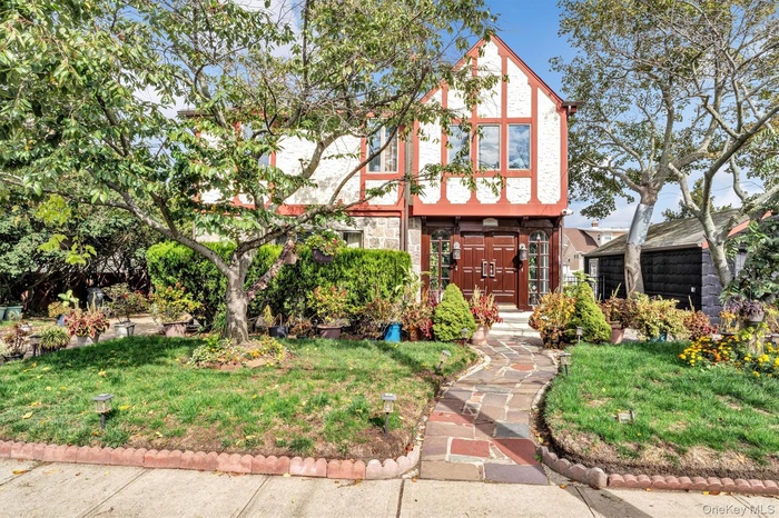 English style home featuring a front lawn and stone siding