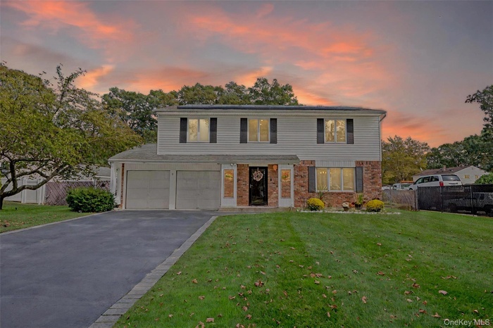 View of front facade with brick siding, asphalt driveway, and an attached garage