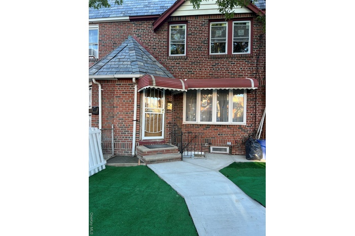 View of front of property featuring brick siding, a high end roof, and a front lawn