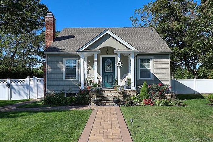 Cape-style home featuring a shingled roof and a chimney