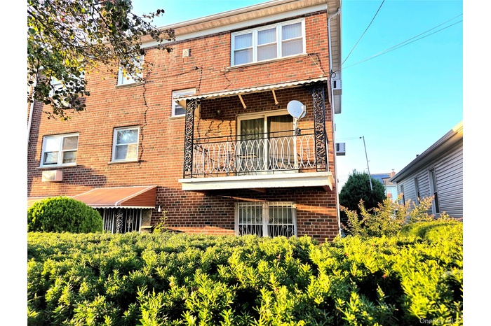 Back of house with a balcony and brick siding