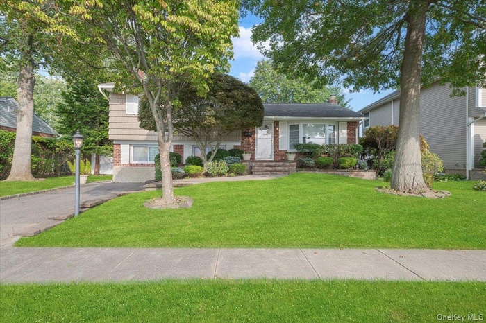 View of front of home featuring brick siding, a front lawn, and a chimney