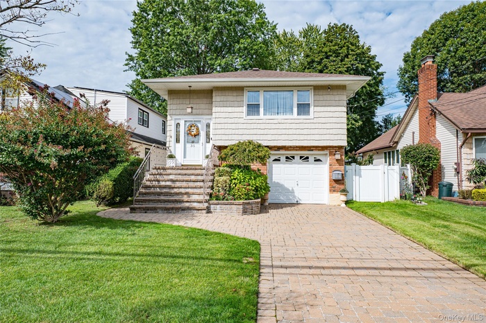 View of front facade featuring brick siding, decorative driveway, an attached garage, and a gate