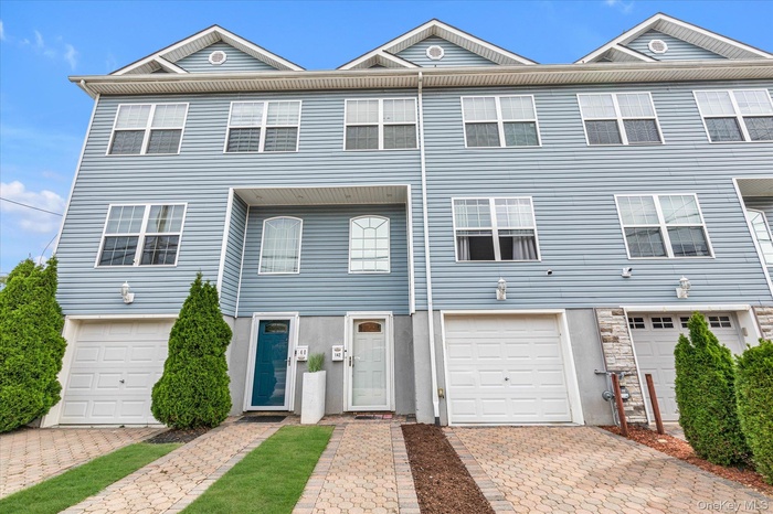 View of front facade featuring a garage, decorative driveway, and stone siding