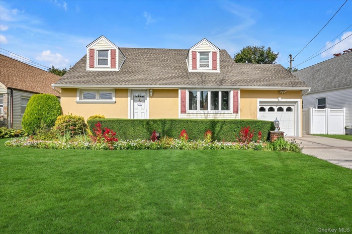 Cape cod-style house with roof with shingles, an attached garage, concrete driveway, and stucco siding