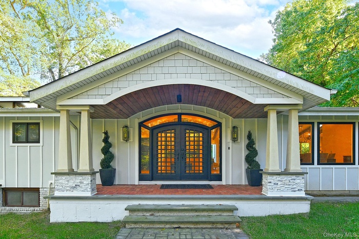 Entrance to property featuring a porch, board and batten siding, and stone siding