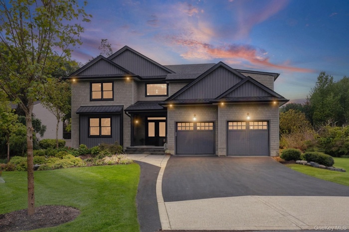 View of front facade featuring asphalt driveway, a lawn, an attached garage, and board and batten siding