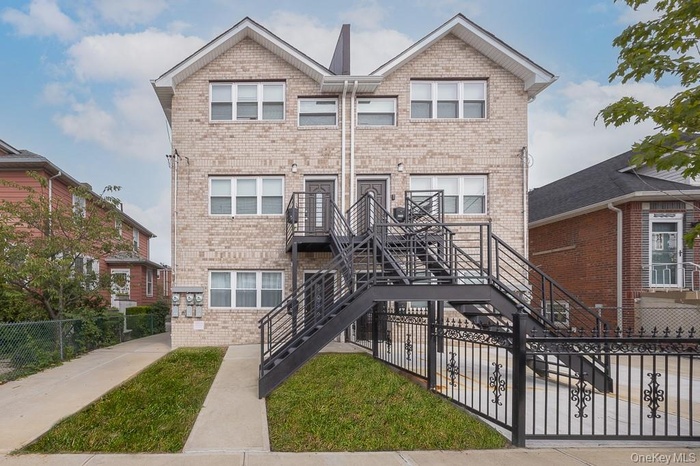 View of front of property featuring a fenced front yard, stairway, and brick siding