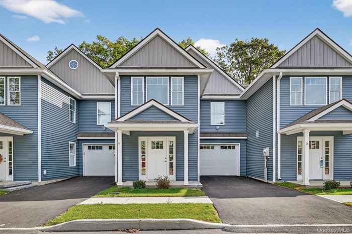 View of front of home featuring board and batten siding, driveway, a metal roof, and a standing seam roof