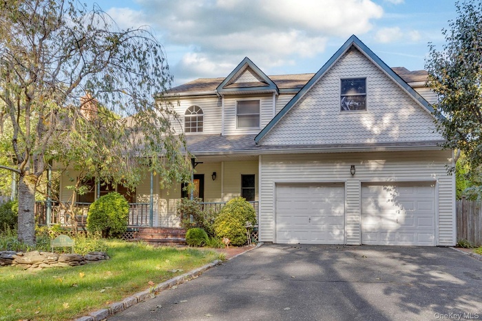 View of front of home with covered porch, driveway, and a garage