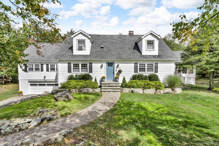 Cape cod home with roof with shingles, a front yard, a chimney, and an attached garage