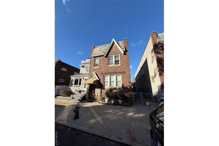Traditional-style home with brick siding, a gate, a chimney, and a high end roof