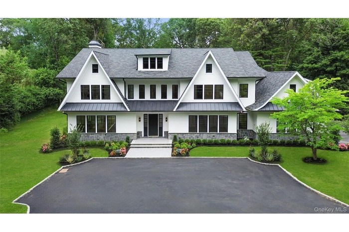 View of front of home with a standing seam roof, roof with shingles, stone siding, and a porch
