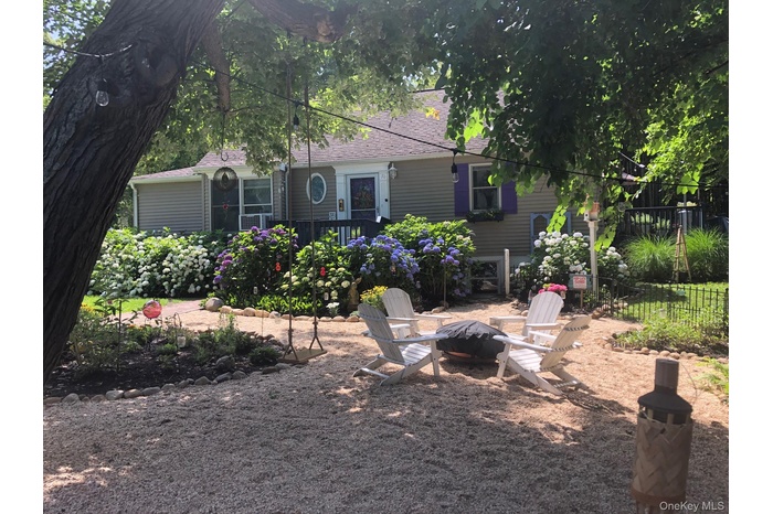 Rear view of property featuring an outdoor fire pit, roof with shingles, and a patio area