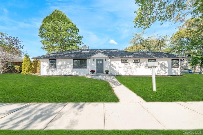 Ranch-style house featuring a front lawn, a chimney, and roof with shingles