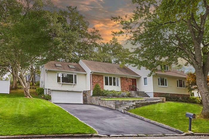 View of front of home featuring a front lawn, asphalt driveway, an attached garage, and roof with shingles