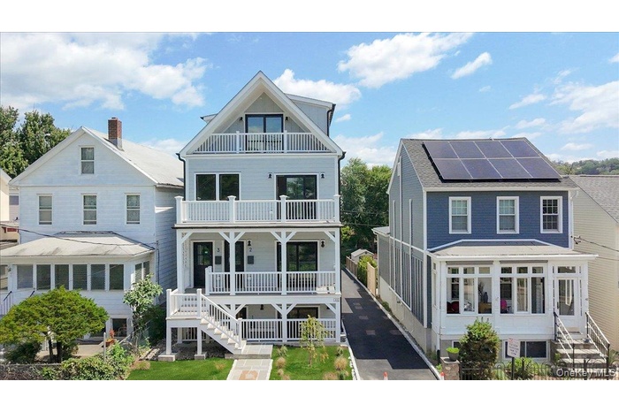 View of front of home with a balcony, a porch, stairs, and roof mounted solar panels