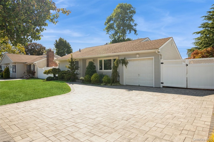 Ranch-style house featuring a gate, decorative driveway, and an attached garage