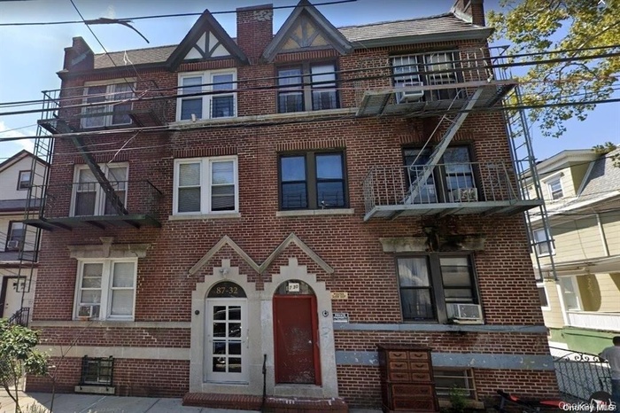 English style home with a chimney and brick siding