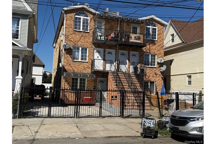 Traditional-style house with brick siding, a gate, a balcony, and a fenced front yard