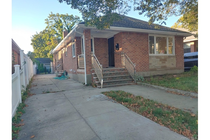 Bungalow with brick siding, a chimney, and concrete driveway