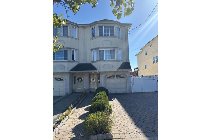 View of front facade featuring brick siding, stucco siding, decorative driveway, and an attached garage