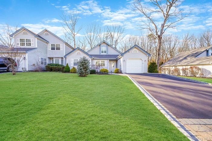 Traditional home featuring driveway, a front yard, and an attached garage