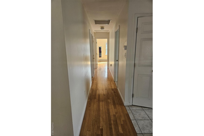 Hallway with light wood finished floors and baseboard heating