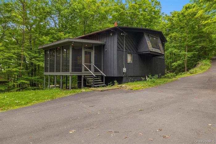 View of front of house with a sunroom and a view of trees