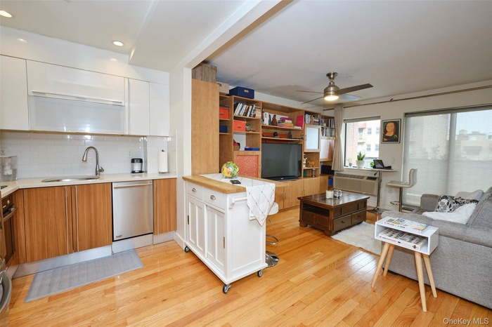 Kitchen featuring dishwasher, a sink, light wood-type flooring, a ceiling fan, and white cabinetry