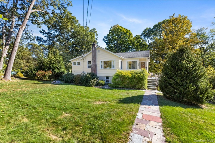 View of front of home with a front lawn, a chimney, and view of lawn