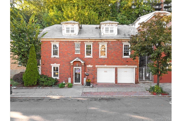View of front of house featuring brick siding, a garage, and driveway